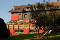 - un bâtiment rouge avec des chaises devant dans l&#39;établissement Hôtel Restaurant Spa Les Jardins De Sophie, à Xonrupt-Longemer