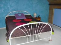 a white bed in a bedroom with a purple book on it at Vacances à Réthoville in Réthôville