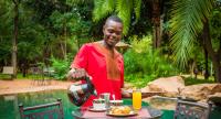a man is standing next to a table with food at Lokuthula Lodges in Victoria Falls