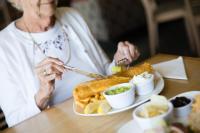a woman sitting at a table with a plate of food at Cliffs Hotel in Blackpool
