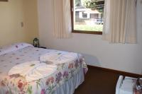 a bedroom with a bed with a floral blanket and a window at Pousada Sino dos Ventos in Campos do Jordão