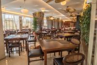 Un restaurante con mesas y sillas de madera y ventanas. en Amazonia Jamor Hotel, en Linda-a-Pastora