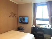 a hotel room with a bed and a tv on the wall at Garden Hotel in Taichung