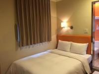 a bedroom with a bed with white sheets and a window at Garden Hotel in Taichung