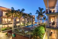 an apartment building with a swimming pool and palm trees at Edgewater Palms Apartments in Paihia