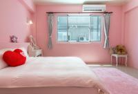 a pink bedroom with a white bed with a red heart pillow at Ciao Life B&amp;B in Taitung City