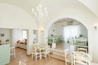 a dining room with tables and chairs and a chandelier at Nissos Thira in Fira