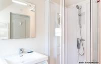 a white bathroom with a shower and a sink at Le Gîte du Port in Roscoff