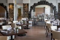 een restaurant met houten tafels en witte stoelen bij Sandy Cove Hotel in Ilfracombe