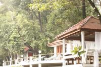 a white house with a porch and chairs and trees at Oon Lee Bungalows in Ko Jum