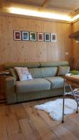 a living room with a green couch and pictures on the wall at Bilocale Ristrutturato in Madesimo