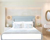 a bedroom with a large bed with a blue headboard at Ikos Dassia in Dassia