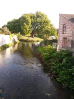 a river next to a brick building and a building at Hôtel du Cygne in LʼAigle