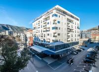 Un edificio alto y blanco con estacionamiento en una ciudad. en Hotel Mostar, en Mostar