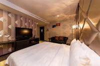 a bedroom with a large white bed and a television at The Riverside Hotel Fashion in Kaohsiung
