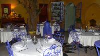 a dining room with white tables and blue chairs at Riad Le Lieu in Tiznit