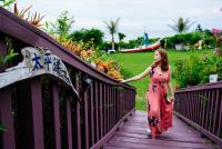 a woman in a red dress walking down a wooden bridge at Sea-Hi B&amp;B in Yanliau