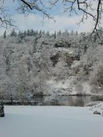 a snow covered hillside with a lake and trees at Hotel Zur Fernmühle in Ziegenrück