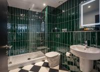 a green tiled bathroom with a toilet and a sink at ABode Manchester in Manchester