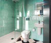 a green tiled bathroom with a toilet and a sink at ABode Manchester in Manchester
