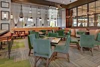 un restaurante con sillas y mesas verdes y un bar en The Grove Hotel, en Boise