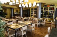 Un restaurante con mesas, sillas y botellas de vino. en Apartment Hotel Marchesini, en Rávena
