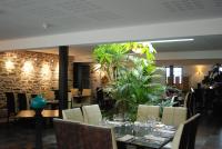 a dining room with tables and chairs and plants at Hotel De France in Pontorson