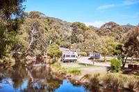 a rv parked next to a river with trees at Lorne Foreshore Caravan Park in Lorne