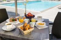 a table with breakfast foods and drinks on a table by a pool at Best Western PLUS Elixir Grasse in Grasse