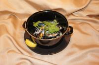 a black pot of food with vegetables and a lemon at Zaliasis slenis - Self check-in hotel - Free parking in Klaipėda
