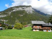 a house in a field with a mountain in the background at Apartment La Tibolire in Sixt