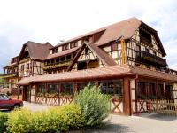 un gran edificio de madera con un coche aparcado delante de él en Hotel Restaurant Au Parc des Cigognes, en Kintzheim
