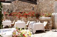 un ristorante con tavoli bianchi e fiori rossi di L’Hermitage Hotel & Spa a Orient