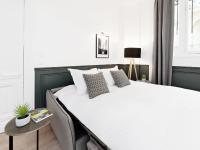 a bedroom with a large white bed with a table at LivinParis - Luxury 3 Bedrooms République I in Paris