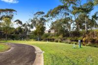 a winding road in a field with a house in the background at Lorne Foreshore Caravan Park in Lorne