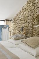 a bedroom with two beds and a stone wall at Bassiviere Barn Chic in Saint-Étienne-de-Villeréal