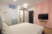 a bedroom with a white bed and a flat screen tv at Fasiter B&amp;B train station in Hualien City