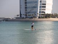 a man standing on a paddle board in the water at Jumeirah Mina Al Salam Dubai in Dubai