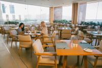 Dos mujeres sentadas en mesas en un restaurante en TMS Hotel Da Nang Beach, en Da Nang