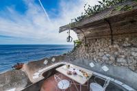a table and chairs on a stone wall next to the ocean at Casa Claudius - Positano in Positano