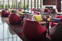 a lobby with red chairs and tables and windows at Beijing Hotel Minsk in Minsk