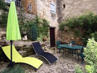 a patio with a table and chairs and an umbrella at Au coeur de Beynac, une maison de caractère avec jardin terrasse in Beynac-et-Cazenac