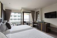 a hotel room with two beds and a desk and a television at Krabi Heritage Hotel in Ao Nang Beach
