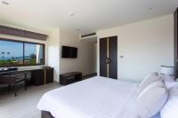 a bedroom with a white bed and a desk and a window at Krabi Heritage Hotel in Ao Nang Beach