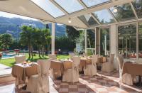 a restaurant with tables and chairs in a conservatory at Hotel Savoy Palace - Tonelli Hotels in Riva del Garda