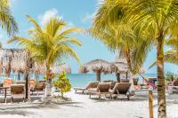 a group of chairs and palm trees on a beach at Zomay Beachfront Holbox in Holbox Island