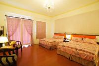 a hotel room with two beds and a chandelier at Garden Rose Homestay in Taitung City