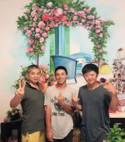 a group of three men standing in front of a floral arch at Garden Rose Homestay in Taitung City
