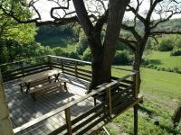 a wooden bench sitting on a deck next to a tree at Gîte de caractère en pleine nature in Bourg-de-Visa