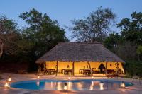 a hut with a thatched roof and a pool at Selous River Camp in Kwangwazi